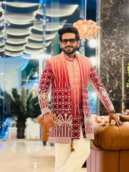Ready for a wedding ceremony in a stunning red and pink shaded sherwani. The geometric patterns and rich colours make a bold statement, perfect for a grand celebration.