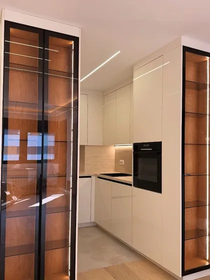 I believe in showing off your beautiful crockery. This is a custom-built display unit featuring tinted glass doors, a dark wood frame, and integrated LED lighting to create a stunning focal point in the kitchen.