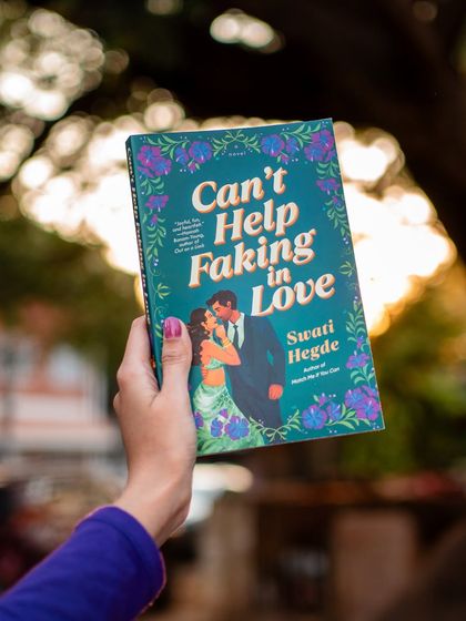 A beautiful shot of the *Can't Help Faking in Love* cover against a sunset. This book is about a woman with Bollywood roots who hires a barista as her fake boyfriend for a wedding.