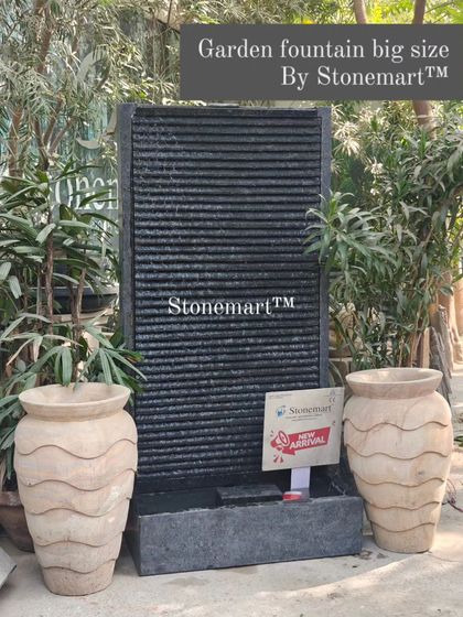 A large 5-foot granite garden fountain, flanked by decorative stone vases. This contemporary piece is fully chiseled by hand and adds life to any modern decor.