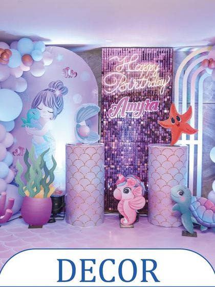 A complete mermaid-themed decor setup for a birthday party. This backdrop includes a shimmering sequin panel, a neon "Happy Birthday" sign, and adorable sea creature props to create a perfect underwater photo zone.