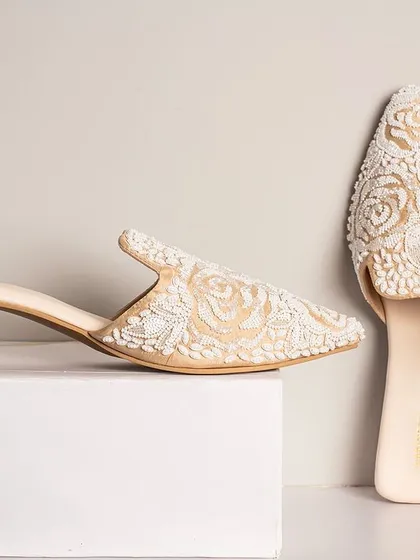 For a touch of pure elegance, these white floral embroidered mules are the perfect choice. The delicate craftsmanship makes them a beautiful addition to any light-coloured ensemble.