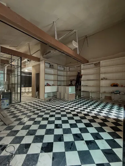 The design process is rarely glamorous, but it is where the magic begins. This behind-the-scenes shot from a retail site shows the raw potential of a space, with the classic checkerboard flooring laid and the custom shelving units beginning to take shape.