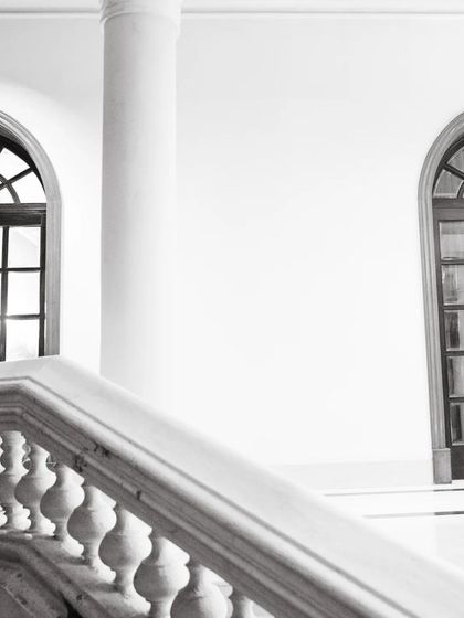 A stunning architectural shot in black and white, with the couple framed by a grand arched window. This creates a dramatic, cinematic, and elegant portrait.