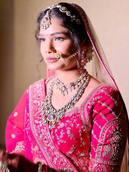 A beautiful bride in a bright pink lehenga. She chose a heavy, ornate kundan set with a matching matha patti and nath to create a truly grand and traditional bridal look.