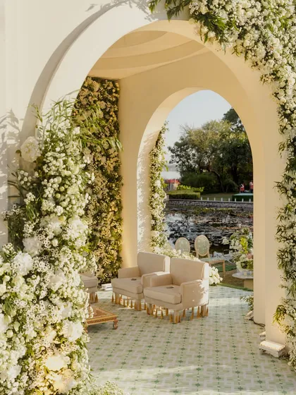 An archway completely covered in white flowers creates a stunning entrance to the mandap area. This immersive floral experience makes guests feel like they are stepping into a secret garden.