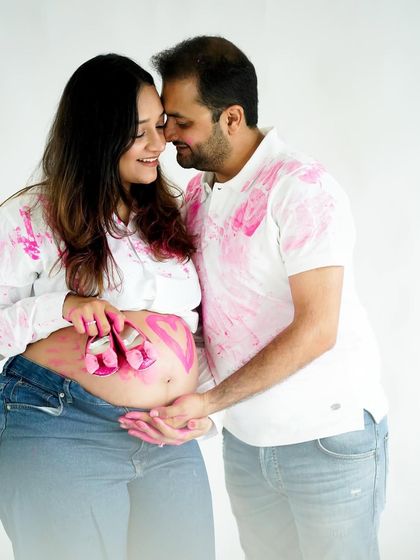 A sweet pose from the gender reveal shoot, with tiny baby shoes dipped in pink paint resting on the baby bump.