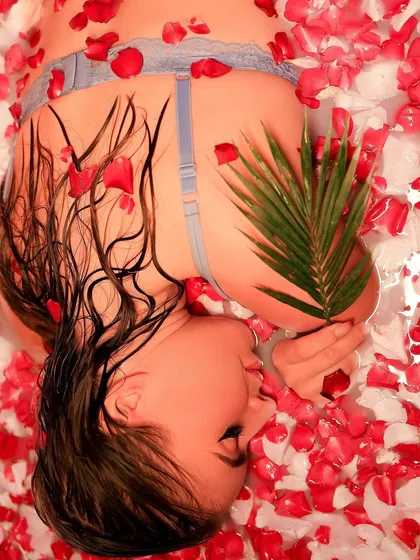 Another perspective of the milk bath shoot, with the model lying upside down, a palm leaf adding a touch of green to the red and white palette.