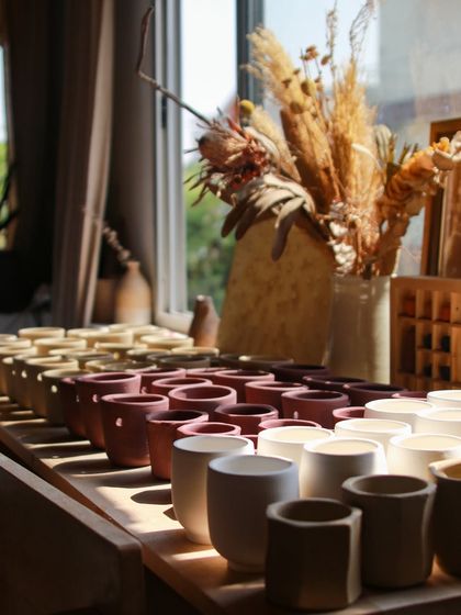 Rows of freshly thrown test cups drying in the sun, each one a small canvas for my experiments with slips, oxides, and glazes.
