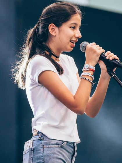 Confidence on stage! This young singer commands the microphone at the Art Mumbai event, a testament to the performance skills we nurture.