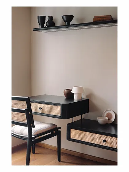 In this guest bedroom, function and beauty coexist in a compact footprint. A floating study desk and shelf in black burnt wood offer a sleek workspace, while the use of natural cane and a simple color scheme keeps the room feeling open and serene.