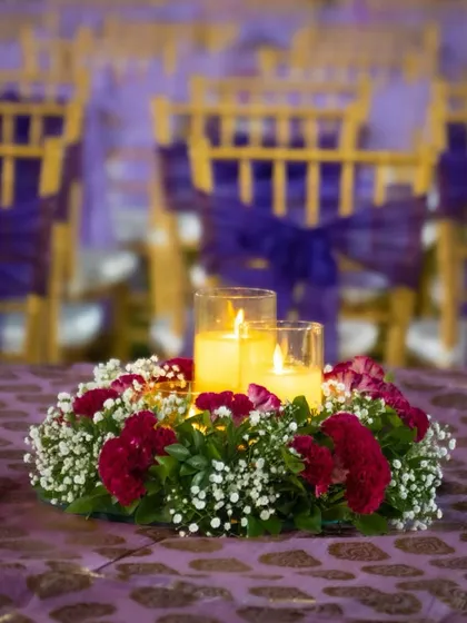 A close-up of our table centerpiece design, featuring warm candles surrounded by a wreath of fresh red and white flowers, adding a touch of romance to the guest tables.