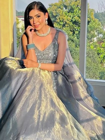 A client sitting by a window, the natural light catching the beautiful shimmer of her grey-blue rental gown.