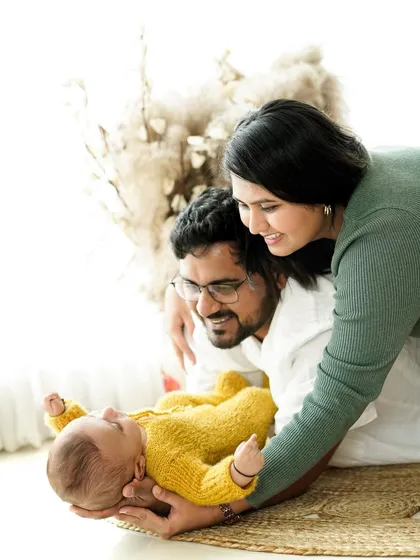 A beautiful family admiring their newest member. This pose shows the love and wonder of new parents as they interact with their baby.