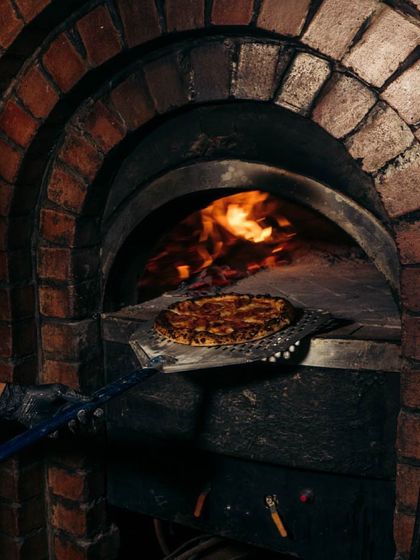 Our pizzas love the spotlight just as much as they love the oven. Here's a classic pepperoni getting its final turn in the intense heat of the brick oven.