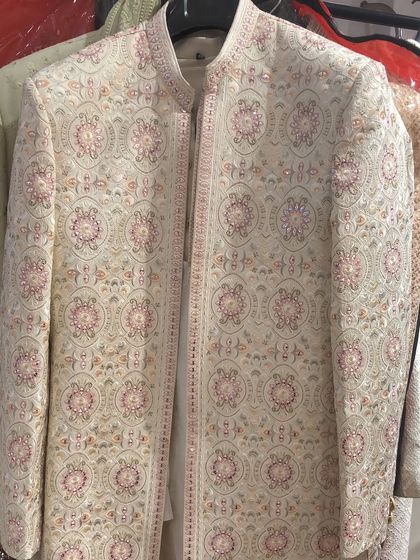 A beautiful sherwani jacket with intricate pastel-colored floral embroidery, perfect for a day wedding.