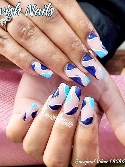 A modern abstract design in shades of blue on square-shaped nails.