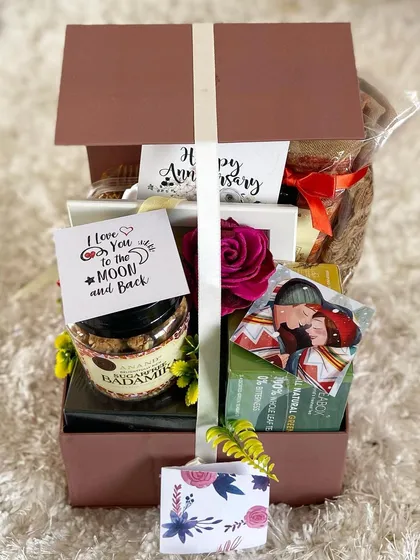 A beautifully packaged anniversary hamper ready to be sent. The elegant box is tied with a ribbon and filled with romantic gifts and treats to help a couple celebrate their special day.