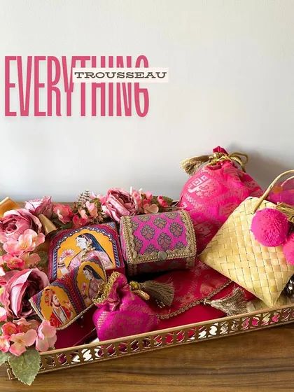 This is my "Everything Trousseau" tray in a regal Rani Pink. It’s a complete set for a bride, featuring a potli, cane bag, bangle case, and more, all curated to bring a touch of royal elegance to her new beginning.