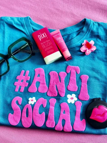 A fun, themed flatlay with a quirky 'Anti-Social' t-shirt and matching pink beauty products. This shows my playful side and ability to create content around a specific mood or phrase.