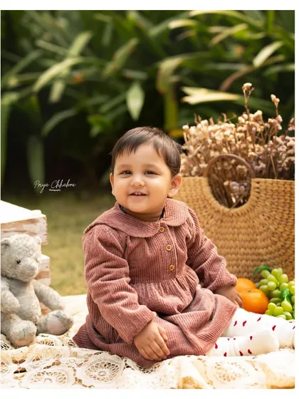 There's something special about an outdoor session, especially for a first birthday. We set up a cozy picnic with a teddy bear, fresh fruits, and soft blankets to create a dreamy, natural setting for this little one's milestone portraits in a Gurugram park.