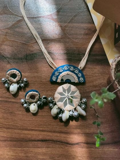 This handcrafted mirror work necklace set is made with a combination of fabric, thread work, and cowrie shells. The design is inspired by traditional Gujarati jewelry, perfect for garba nights.