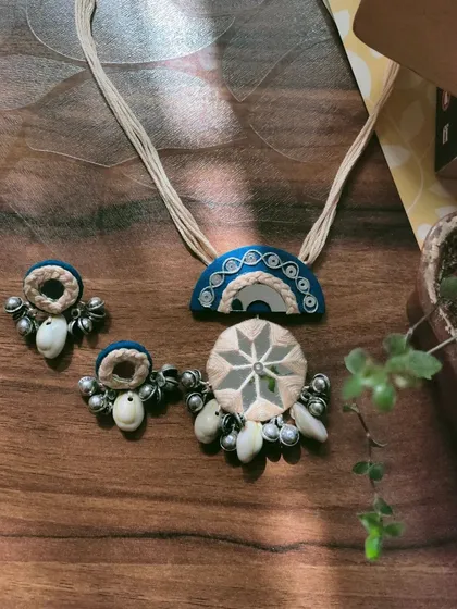 This handcrafted mirror work necklace set is made with a combination of fabric, thread work, and cowrie shells. The design is inspired by traditional Gujarati jewelry, perfect for garba nights.