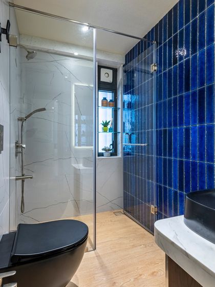 A modern washroom from the Filigree House project. The vibrant blue vertical tiles create a stunning feature wall, contrasted with a sleek black toilet and vessel sink for a bold, contemporary look.