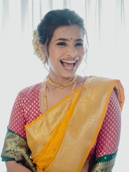 The pure, uninhibited joy of a bride on her wedding day. Her minimal makeup, featuring a simple bindi and glowing skin, perfectly complements her traditional Paithani saree.