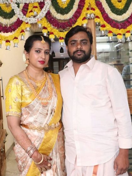 A couple at their housewarming. The client's makeup is festive, with a bold red lip that stands out against her beautiful off-white and gold saree.
