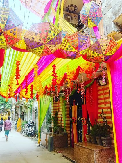 A vibrant street-side tent entrance decorated with Rajasthani umbrellas and colourful drapes for a Mehendi or Haldi function.