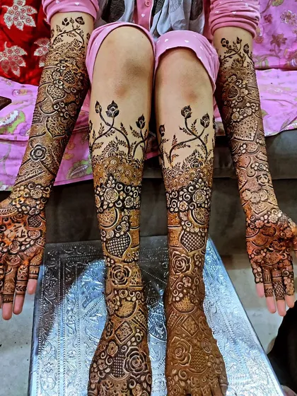 A full bridal look with matching designs on hands and feet, featuring delicate vines climbing up the legs.