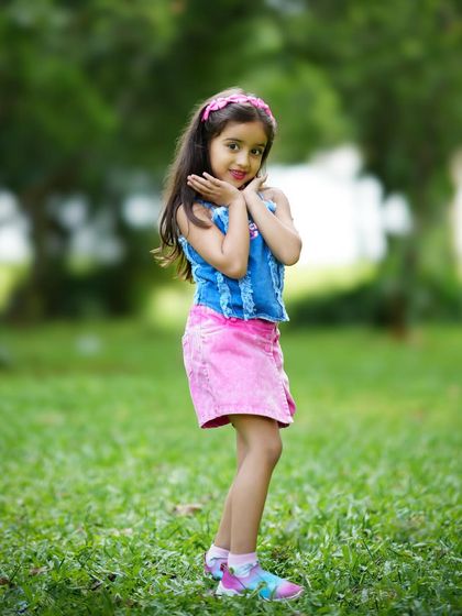 A pretty girl posing playfully in a park. Outdoor shoots are perfect for capturing the natural energy and joy of childhood.