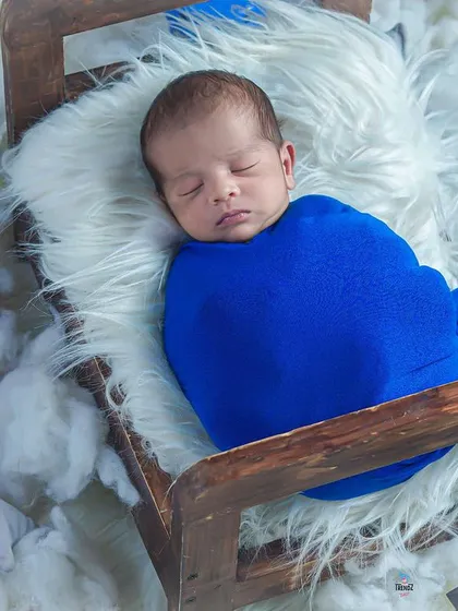 A wider shot of the dreamy 'baby in a bed' setup, showing the full scene with the lantern and purple flowers.