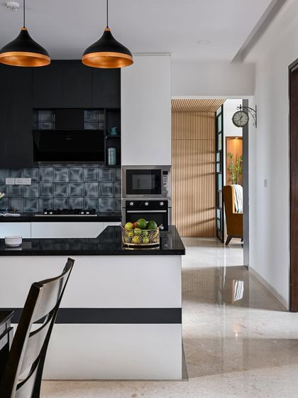 An unconventional kitchen design where the wall units are a darker color (black) than the base units (white). This works well in an open kitchen with minimal wall cabinets, creating a bold and modern statement.
