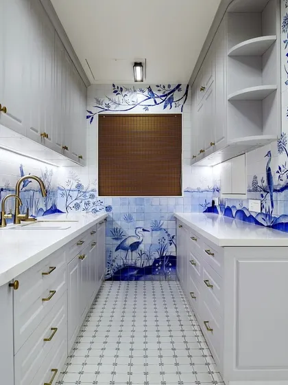 The full view of this galley kitchen showcases the immersive experience created by the hand-painted tiles. The design wraps around the room, making it feel like you are stepping into a story.