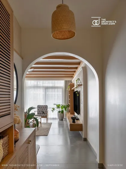 An arched entryway leads into the living room of the 'Cover me in Sunshine' project, revealing a space with exposed ceiling beams and modern cottage charm.