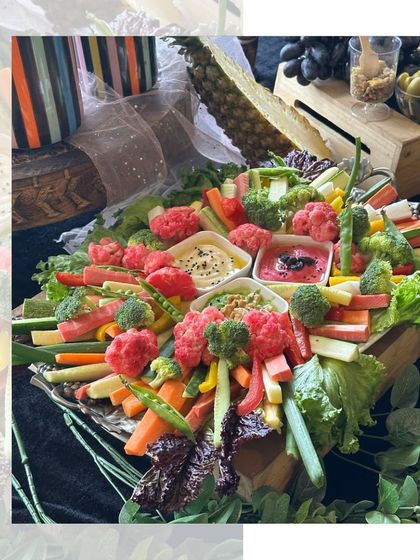 A fresh and healthy crudités platter as part of a larger grazing table. We arrange a rainbow of fresh vegetables like carrots, cucumbers, and bell peppers around creamy dips for a crisp and light option.