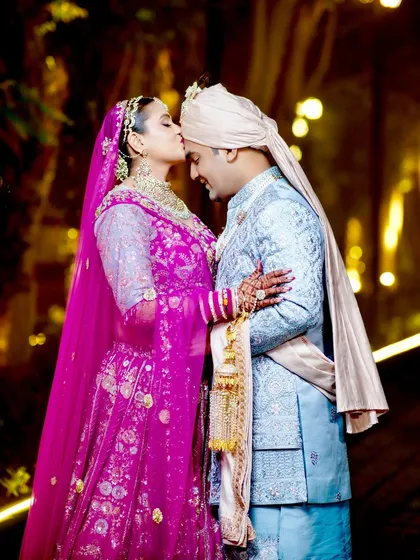 A classic romantic pose, with the bride kissing the groom's forehead.