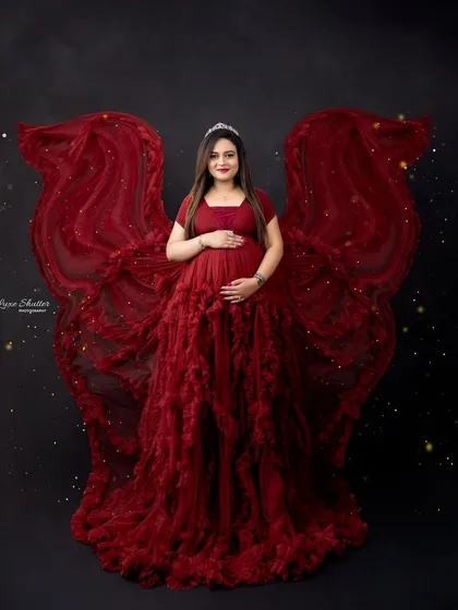 For a truly show-stopping portrait, we can create dramatic effects like these fabric wings. In a bold red gown against a dark backdrop, this style is all about celebrating the power and confidence of the mother-to-be.