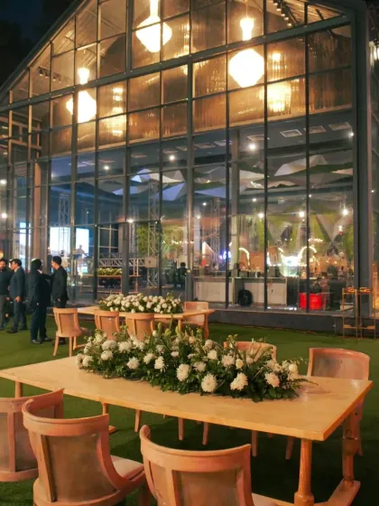 A modern glasshouse venue setup for an evening reception, showcasing the beautiful interplay of indoor and outdoor spaces.