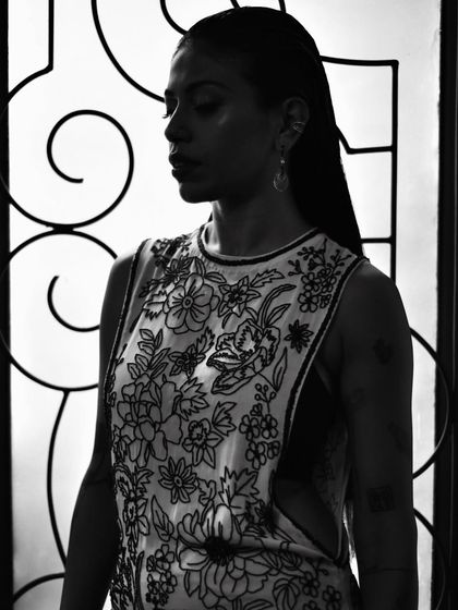 A black and white portrait of Anasuya Sengupta where the light highlights the beautiful embroidery on her dress.