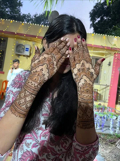 A happy client showing off her beautiful back-hand mehendi. The design is elegant and perfect for any festive occasion.