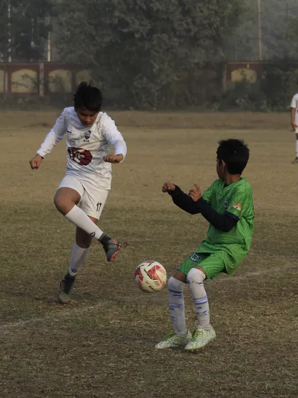 Two players challenging for the ball in a competitive youth league fixture. Every match is a learning experience.