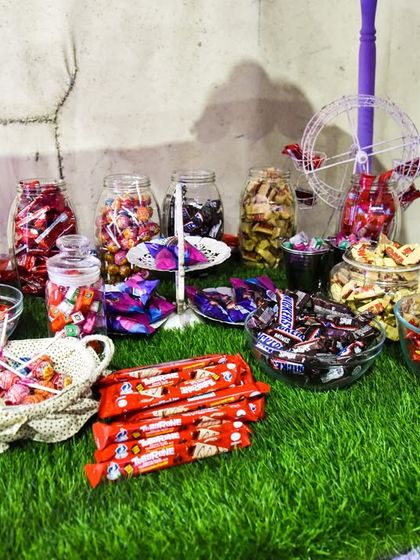 A candy bar overflowing with a wide assortment of chocolates, lollipops, and other sweets for guests to enjoy at the Candyland party.