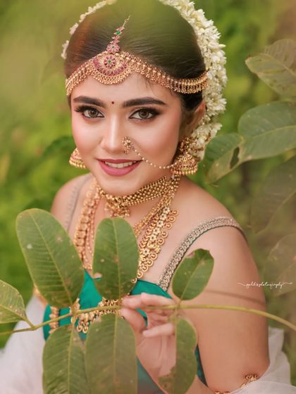 Inspired by the grandeur of Bahubali, this "Sakhi" look features a model in a unique orange and green dhoti-style saree. The outdoor setting and regal jewelry complete the ancient princess aesthetic.