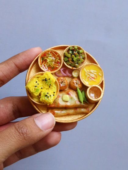 A close-up of a Kathiawadi thali, highlighting the tiny dhokla, thepla, and various vegetable curries.