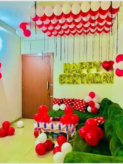 A simple yet effective living room decoration. Red and white balloons on the ceiling and a 'Happy Birthday' foil banner transform the space into a party zone.