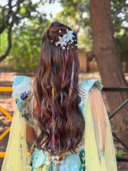 For a fun, carnival themed Mehendi, I created this half updo with flowing waves and added colorful thread extensions and whimsical blue floral clips. This style is all about expressing personality and embracing a vibrant, playful theme.