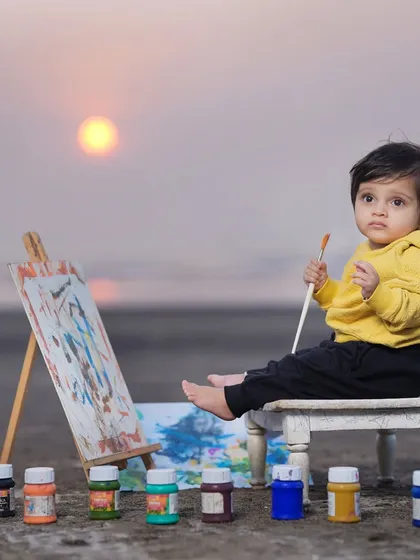 A mini artist creating a masterpiece on the beach at sunset. This themed outdoor shoot combines creativity with the beautiful natural backdrop of the sea and sky.